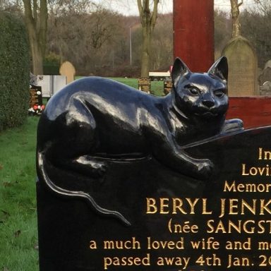 Polished black granite cat carved onto the top of a gravestone