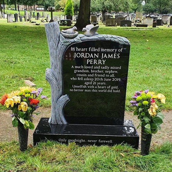 Black granite memorial with carved and painted tree and bird feature, silver lettering