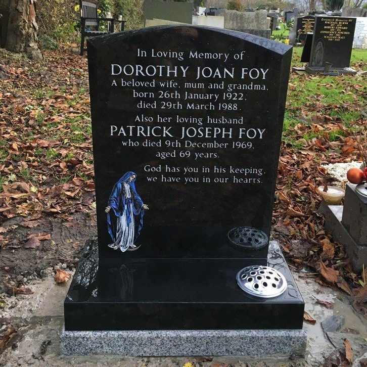 Black oval shaped headstone with chamfered sides. High resolution etching of Our Lady painted white and blue